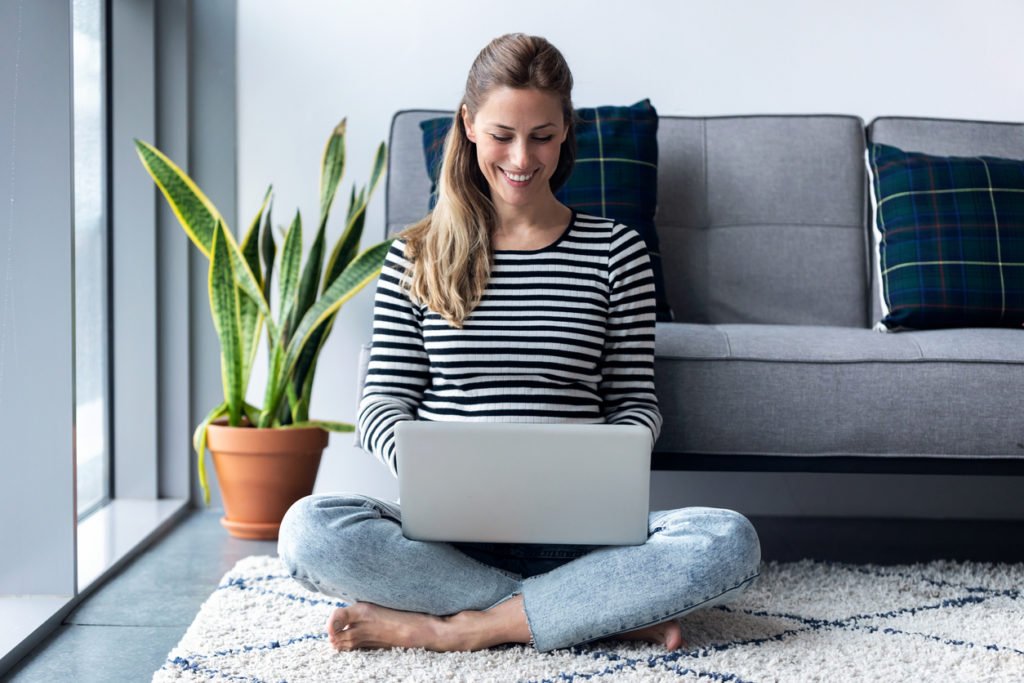 Pretty young woman using her laptop while sitting on the floor at home. Shot of pretty young woman using her laptop while sitting on the floor at home.